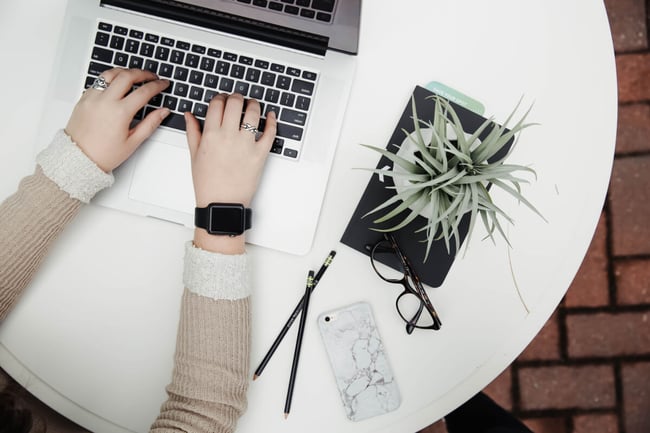 Woman typing with laptop on table with a plant. Picture by Corinne Kutz. https://unsplash.com/?photo=tMI2_-r5Nfo