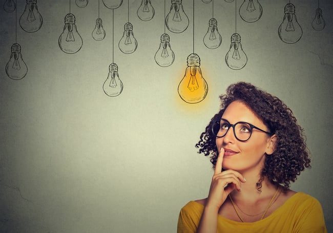 Woman in glasses thinking with lit idea bulb above her head